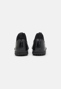 Svarta sportskor med texturerad design, elastiska överlagringar och dragflikar på hälen. Gummisula med mönster för bra grepp.