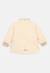 Φωτεινό μπεζ παιδικό μπουφάν με μακριά ραγκλάν μανίκια, πλεκτές μανσέτες και κούμπωμα με κουμπιά στον λαιμό. Διαθέτει μικρό λογότυπο στην πλάτη.