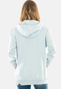 Felpa con cappuccio azzurro chiaro, maniche lunghe, polsini e orlo a coste. Presenta una tasca a marsupio e un'etichetta sul lato sinistro in basso.