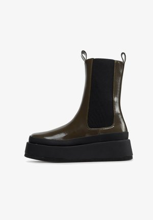 Dunkelolivgrüner Chelsea-Stiefel mit hoher Plattform, glänzendem Finish, schwarzen elastischen Seitenpaneelen und dicker schwarzer Sohle.