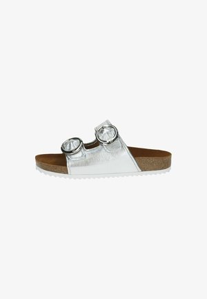 Silver metallic slide sandal with two circular buckles, cork-latex footbed, and white textured sole. Flat design without heel.