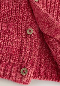 Cardigan en tricot rose avec un motif texturé, comportant une fermeture à boutons avec un design floral et une poche sur le côté gauche.