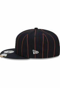 Schwarze Baseballmütze mit orangen vertikalen Streifen, besticktes Logo an der Seite, flacher Schirm und strukturierter Stoff. Mit einem Aufkleber auf dem Schirm.