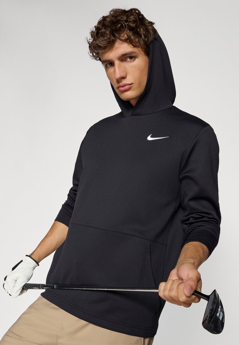 Black Nike hooded sweatshirt with a textured finish, featuring a front pocket and a white logo on the chest, paired with a golf club.