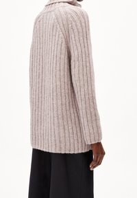 Ljusrosa ribbad tröja med hög krage och långa ärmar. Tillverkad av mjukt material med en texturerad yta. Bakvy som visar en avslappnad passform.