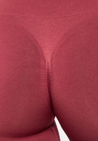 Czerwone legginsy bezszwowe z wysokim stanem, prążkowaną teksturą i konturowym wzorem z tyłu dla lepszego dopasowania i podkreślenia sylwetki.