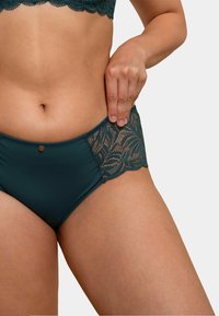 Culotte en coton teal avec des accents en dentelle au niveau de la taille, présentant un bord festonné et un bouton décoratif en métal à l'avant.