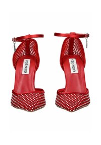 Červené lodičky Steve Madden s špičatou špičkou, stříbrnými hroty, síťovinovými stranami a kotníkovými řemínky s malými stříbrnými klíčovými šarmy.