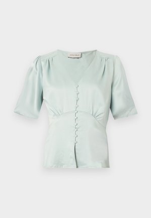 Blouse en satin bleu clair à manches courtes avec un col en V, des boutons recouverts de tissu sur le devant, des épaules légèrement bouffantes et une taille cintrée.
