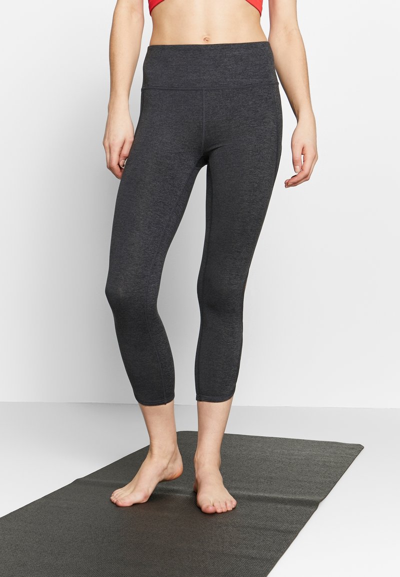 Mörkgrå träningscaprileggings med hög midja, gjorda av ett stretchigt material, med platta sömmar och en jämn yta.