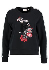 Veste noire avec un "R" en sequins et des motifs floraux en rouge, blanc et noir. Dotée d'accents gris sur les manches et d'un ourlet côtelé.