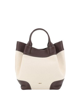 Cream fabric tote bag with dark brown leather handles, trim, and bottom corners, featuring a small gold brand logo on the front.