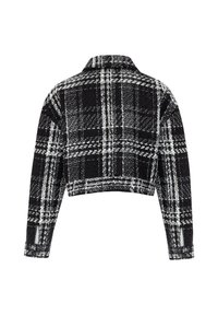 Veste courte à carreaux noir et blanc avec manches longues et col classique, vue de dos sur fond blanc.