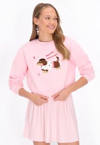 Różowa bluza z kapturem z brązowym, kreskówkowym psem, napisem "Mymo Pop Happy Puppy" oraz kolorowymi gwiazdkami. Miękki materiał i ściągacze na rękawach.