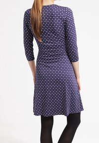 Námořnický modrý šaty s bílým diamantovým vzorem, rukávy do tří čtvrtin, dobře padnoucí design, rozšířené na lemu, hladká textilní struktura.