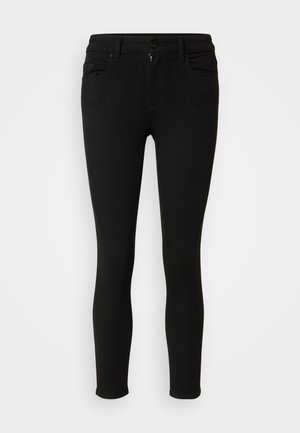 Jeans skinny noirs en matériau extensible, avec une fermeture éclair, un bouton de fermeture et deux poches avant. Texture lisse et design ajusté.