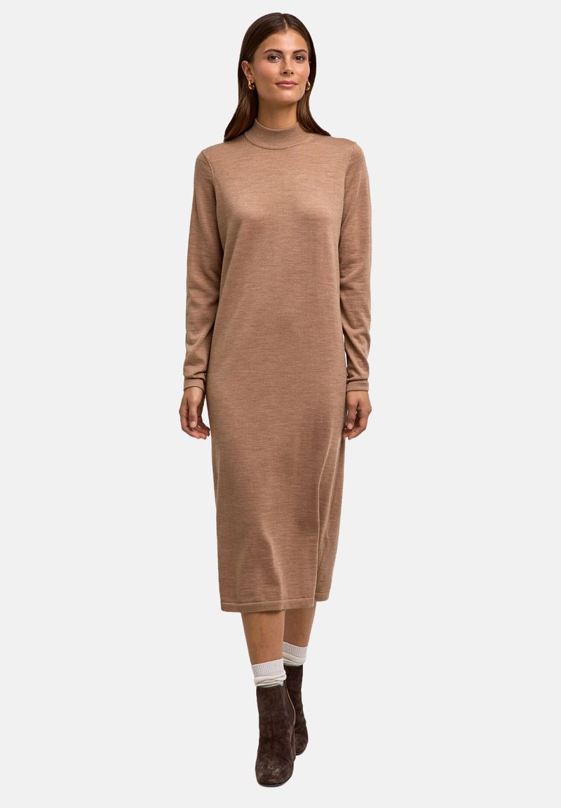 Abito lungo a maniche, in maglia marrone con collo alto, caratterizzato da una vestibilità comoda e una texture liscia, abbinato a stivaletti neri e calzini bianchi.