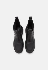 Bottines noires avec une tige en cuir lisse et un motif serpent texturé, semelle en caoutchouc, languettes de tirage et bout arrondi. Conçues pour le confort et la durabilité.
