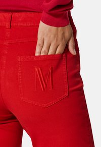 Rote Denim-Hose mit passgenauer Passform, aus strukturiertem Material und mit einem gestickten "M" auf der rechten Gesäßtasche.