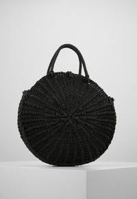 Rund svart vävd väska med texturerad yta, utrustad med två korta handtag och e cirkulär form, tillverkad av naturliga material.