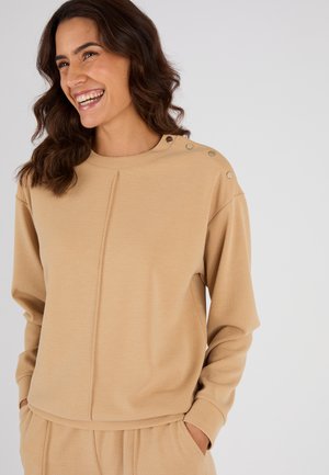 Beige sweatshirt met textuur en lange mouwen, voorzien van decoratieve knopen op de schouder, een ronde halslijn en een losse pasvorm.