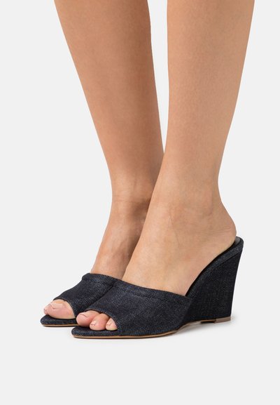 Denim wedge sandals with an open toe, dark blue color, textured fabric, and contoured heel design.