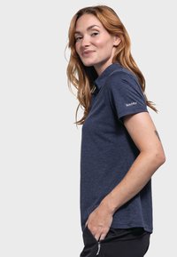 Dunkelblaues Poloshirt aus strukturiertem Stoff, mit Kragen und kurzen Ärmeln. Ein Logo ist auf dem linken Ärmel sichtbar.