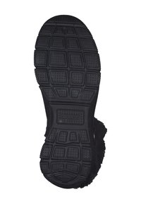 Semelle en caoutchouc noir avec un motif texturé, comprenant des indentations rectangulaires et circulaires pour une traction et une stabilité optimales.
