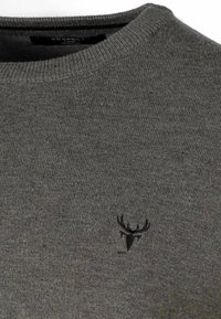 Grå stickad tröja med rundad halsringning, som har en liten svart älg-logotyp på bröstet. Tyget har en slät textur.