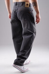 Graue Jeans aus Denim mit lockerer Passform, ausgestattet mit einem Lederpatch am Bund, zwei Gesäßtaschen und Kupferrivets, getragen mit weißen Schuhen.