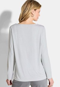 Lichtgrijs languit shirt met dunne witte strepen. Heeft een brede ronde hals en een relaxte pasvorm. Zacht, rekbaar materiaal.