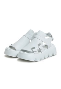 White leather sandals with open toe, cut-out details, adjustable back strap, and chunky white sole for added height.