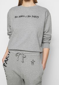 Grijze katoenen sweatshirt met zwarte tekst "No PINKO No PARTY," lange mouwen en bijpassende broek met een logo en trekkoord taille.