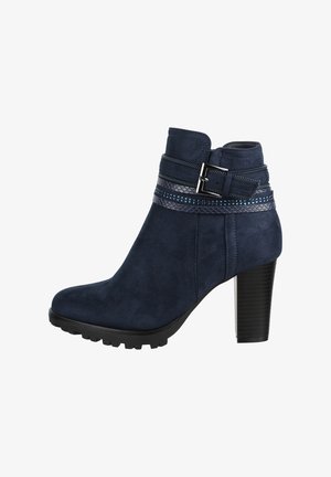 Bottes chelsea en suède bleu marine avec une sangle texturée dotée d'accents métalliques et un talon bloc haut. Comprend une semelle en caoutchouc crantée.