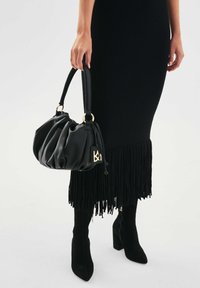 Czarna skórzana torebka o marszczonym wzorze, z złotymi akcentami metalowymi i oznaczeniem logo. Uchwyt jest gładki, a korpus ma miękką fakturę.