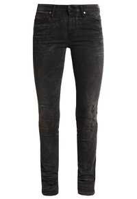 Schwarze, enge Jeans aus Denim mit einer verwaschenen, lädierten Textur und subtilen Nähten. Verfügt über den klassischen Fünf-Taschen-Stil und einen Reißverschluss.