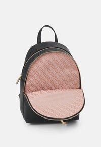 Zwarte leren rugzak met gouden ritsen, open voorvak dat fuchsia stoffen voering onthult met een herhalend geometrisch patroon.