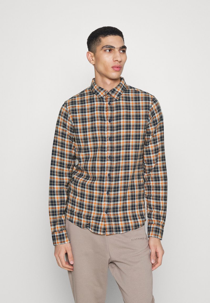 Chemise à manches longues à carreaux avec un motif à damier bleu marine, orange et blanc, col boutonné et coupe ajustée, fabriquée en tissu léger.