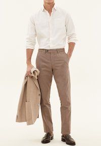 Beige bomulds skjorte med en forlommer, taupe bukser og en lys beige blazer. Brune loafers fuldender outfittet. Simpelt, skræddersyet design.