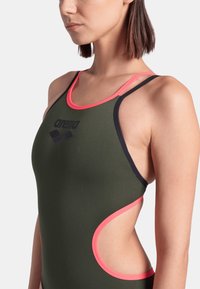 Schwimmschwanz in dunkelgrünem Stoff mit rosa und schwarzem Saum. Verfügt über ausgeschnittene Seiten und ein Logo auf der Vorderseite.