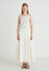 Witte maxi-jurk met geborduurde lijfje, vierkante halslijn en dikke banden. Beschikt over een gladde, vloeiende stof en subtiele gestikte accenten.