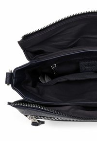 Granatowa skórzana torebka o fakturowanej powierzchni, wyposażona w zamek błyskawiczny oraz materiałowe wnętrze z wieloma przegrodami.