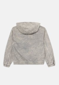 Veste à capuche grise en tissu léger. Caractérisée par une coupe décontractée, des poignets élastiques et une finition texturée. Aucune logo ni motif visible.