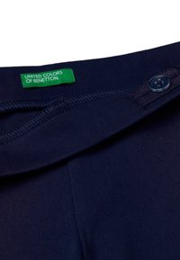 Námořnické modré bavlněné kalhoty s zeleným štítkem "UNITED COLORS OF BENETTON," s knoflíkovou sponou a hladkou, texturovanou tkaninou.