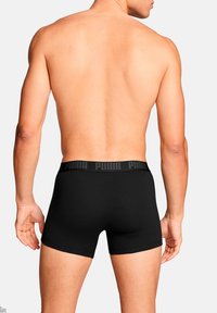 Schwarze Boxershorts mit einem strukturierten Bund, der das "PUMA"-Logo zeigt. Das Kleidungsstück ist eng anliegend und scheint aus elastischem Material gefertigt zu sein.