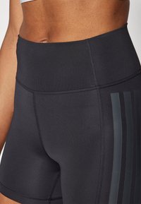 High-waisted black athletic shorts made of stretchy material, featuring vertical stripes on one side and flat seams for comfort.