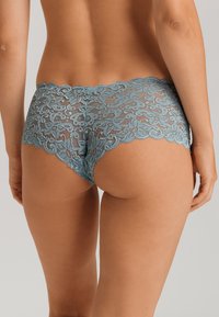 Slip hipster in pizzo blu con bordi a scallop e motivi floreali, caratterizzati da un pannello trasparente e una vestibilità aderente per il massimo comfort.