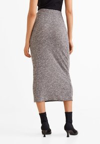 Grauer, taillierter Midirock aus weichem Strickstoff, der eine schlanke Silhouette, einen seitlichen Schlitz und ein hochgeschnittenes Design aufweist.
