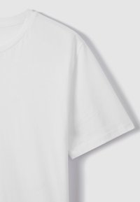 Hvid kortærmet t-shirt med rund hals set forfra på en lys grå baggrund.