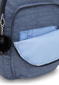 Ljusblå ryggsäck med en texturerad mörkblå yta, ett framfack med en ljusblå klaff och ett svart pälsnyckelband som accent.